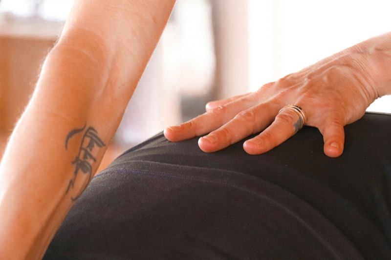 A physiotherapist's hand resting on a patient's lower back.