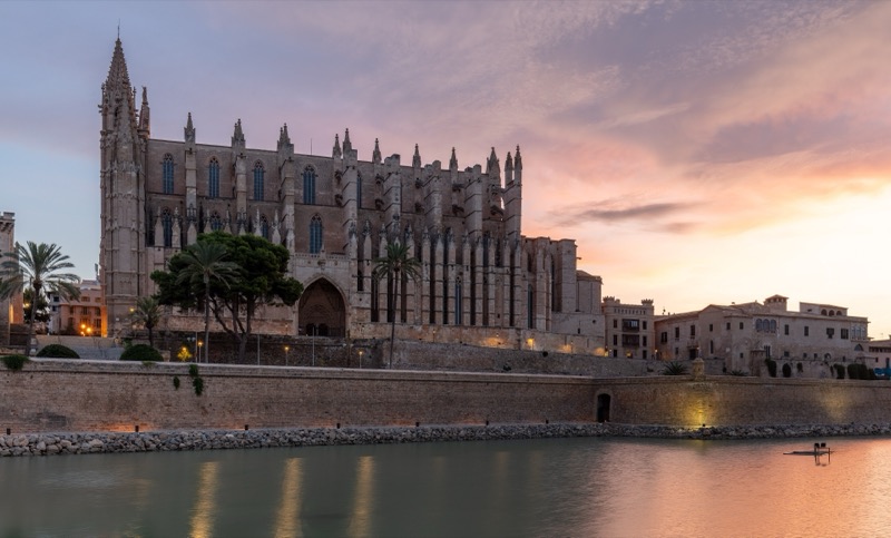 La catedral de Palma al atardecer, con el cielo rosado reflejado en el agua del parque del Mar.