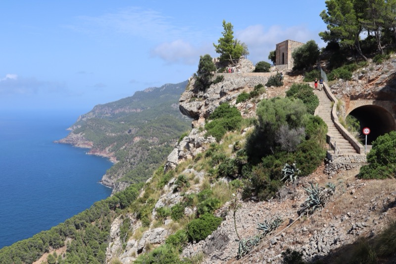 Rugged Serra de Tramuntana coastline with a stone lookout and the blue sea beyond.